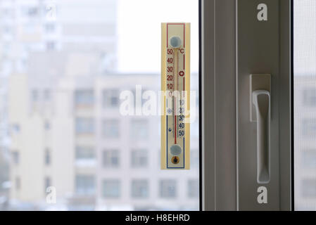 A thermometer, fixed out of the window, shows that it is zero degree celsius outdoor, while it is warm inside the room Stock Photo