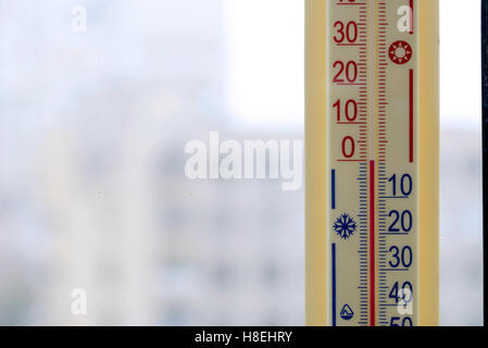 A thermometer, fixed out of the window, shows that it is zero degree celsius outdoor, while it is warm inside the room Stock Photo