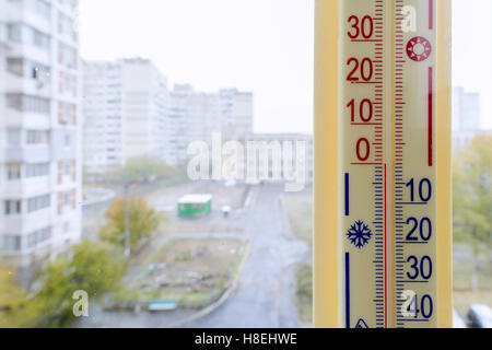 A thermometer, fixed out of the window, shows that it is zero degree celsius outdoor, while it is warm inside the room Stock Photo