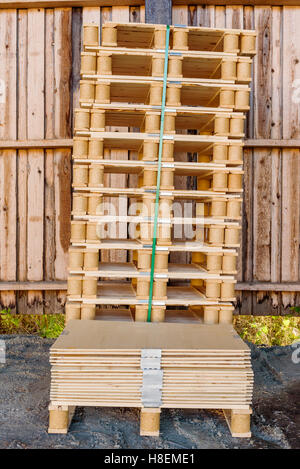 Stack of pallets and pallet material against wooden wall. Stock Photo