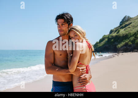 Portrait of happy young woman with her boyfriend on the sea shore. Loving couple on the beach enjoying summer holidays. Stock Photo