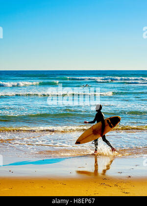 Surfer with surfboard walking on the ocean beach Stock Photo