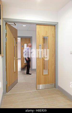 fire doors in a new London office building showing ironmongery, signs and  blurred man passing Stock Photo