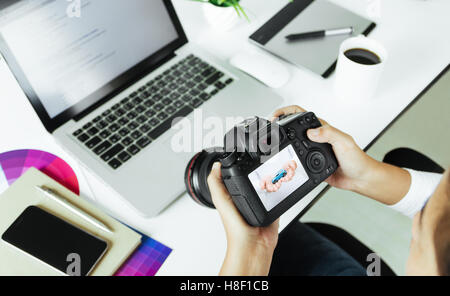 photographer checking dslr camera on desk Stock Photo