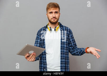 Portrait of amazed frustrated man using tablet computer over gray background Stock Photo
