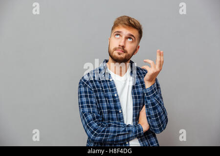 Portrait of a casual thoughtful bearded man standing and looking away isolated on a gray background Stock Photo