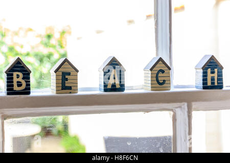 Little beach hut wooden ornaments on window frame composing the word BEACH Stock Photo