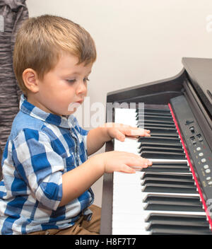 little happy boy plays piano at home Stock Photo