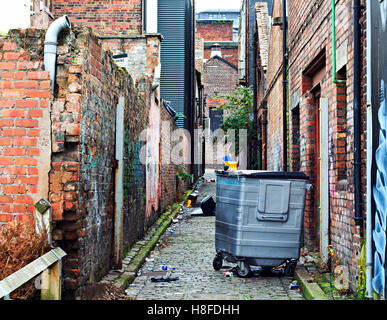 Household rubbish left lying about in a dirty back street cobble stoned  alley Stock Photo