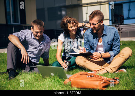 three students sitting on lawn Stock Photo