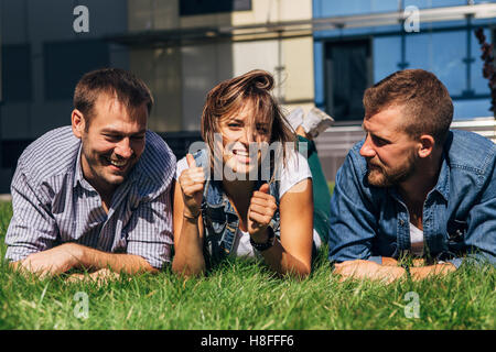 three students lying on the grass Stock Photo