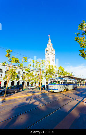 Historic Ferry Building angled in front of a gray vintage F Market tram on rails running along the Embarcadero in San Francisco Stock Photo