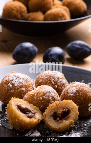 plum dumplings on black plate with sugar icing Stock Photo