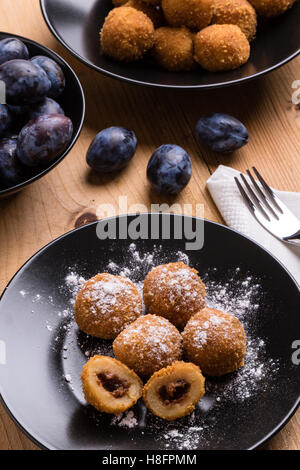plum dumplings on black plate with sugar icing Stock Photo