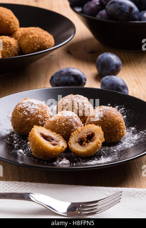 plum dumplings on black plate with sugar icing Stock Photo