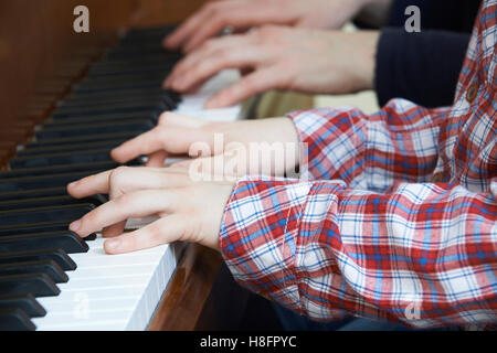 Close Up Of Boy Playing Piano Duet With Teacher Stock Photo