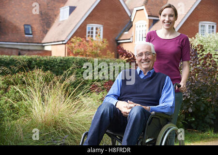 Daughter Pushing Senior Father In Wheelchair Stock Photo