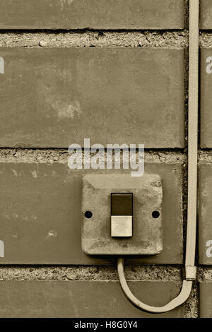 Outdoor electric equipment control industrial button switch wire cable closeup, old aged weathered grungy brick wall background Stock Photo