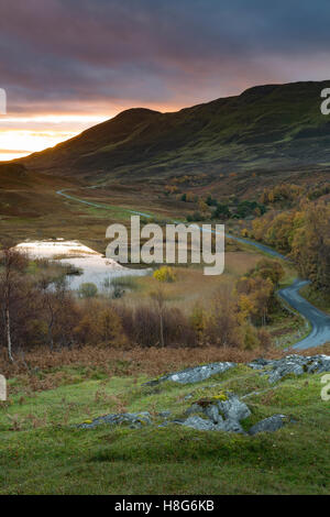A winding country road bends through the landscape at sunrise. Stock Photo