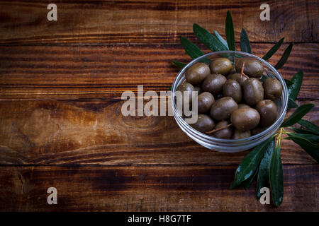 Bowl of purple marinated olives with olive leaves on dark background Stock Photo