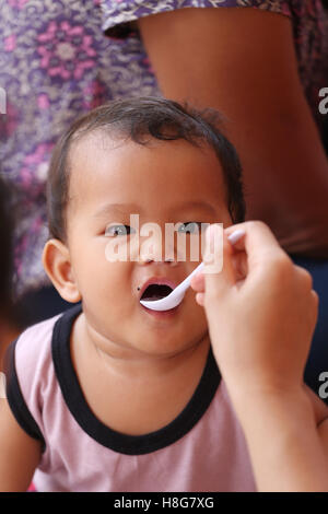 Asian baby eating a dragon fruit with happily,concept of health and foods of the children. Stock Photo