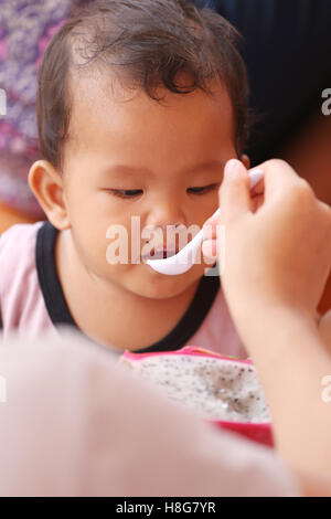 Asian baby eating a dragon fruit with happily,concept of health and foods of the children. Stock Photo