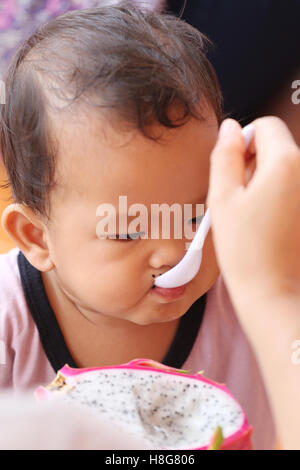 Asian baby eating a dragon fruit with happily,concept of health and foods of the children. Stock Photo