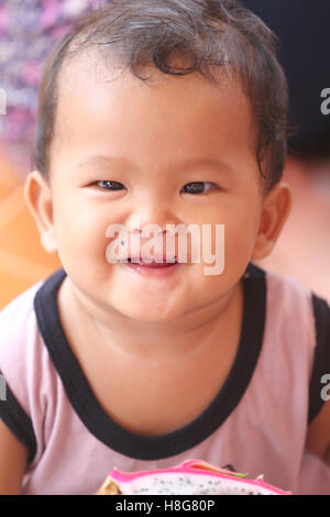 Asian baby eating a dragon fruit with happily,concept of health and foods of the children. Stock Photo