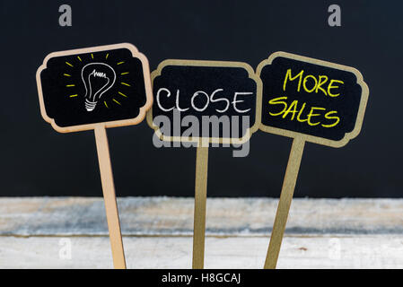 Concept message CLOSE MORE SALES and light bulb as symbol for idea written with chalk on wooden mini blackboard labels Stock Photo