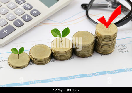 silver coin stack of business graph and have treetop in business growth concept on paper of report assessed income. Stock Photo