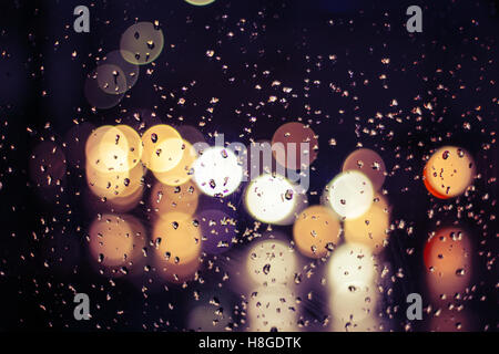 Traffic scene from a wet cristal window with bokeh effect Stock Photo