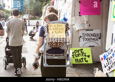 Los Angeles, California, USA. 12th November, 2016. A mother carries her child with a sign on the back of the child carrier at the Anti-Trump March held in Los Angeles, California. Credit:  Sheri Determan / Alamy Live News