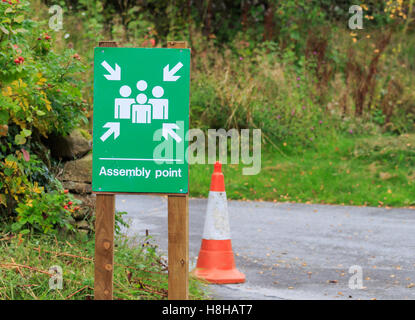 Green and white Assembly Point sign fitted to wooden post Stock Photo