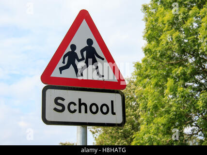 Red and White Triangular School sign with trees and sky background Stock Photo