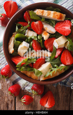 Dietary salad with strawberries, grilled chicken, brie and arugula close-up on the table. vertical view from above Stock Photo