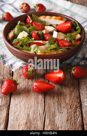 Dietary salad with strawberries, grilled chicken, brie and arugula close-up on the table. vertical Stock Photo
