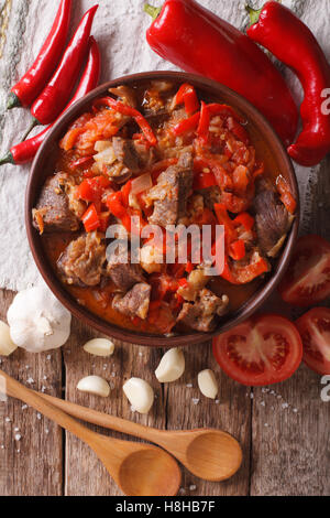 pieces of lamb cooked with onion, tomato and pepper close-up in a bowl on the table. vertical view from above Stock Photo