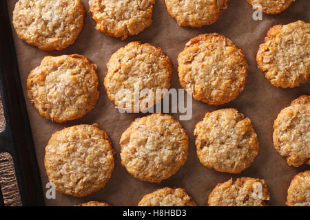 Freshly baked oatmeal Anzac cookies close up on a baking sheet on the table. horizontal view from above Stock Photo