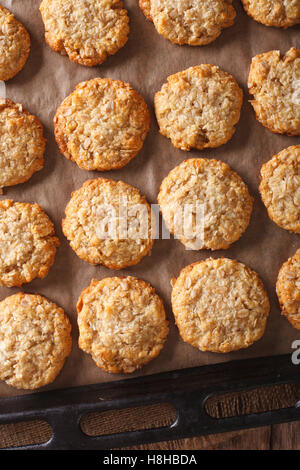 Freshly baked oatmeal Anzac cookies close up on a baking sheet on the table. vertical view from above Stock Photo