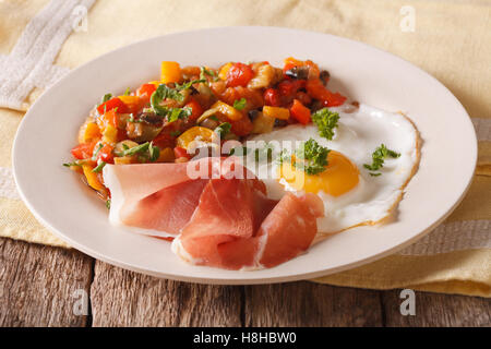 Spanish cuisine fried egg, jamon and vegetable stew on a plate close-up. horizontal Stock Photo