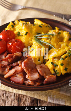scrambled eggs and chives, fried bacon on a plate close-up. Vertical Stock Photo