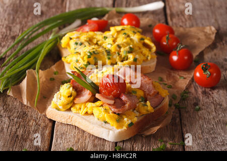 Homemade sandwiches with fried eggs, bacon and tomatoes close-up on the table. horizontal Stock Photo