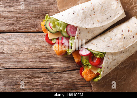 Sandwich roll with fish fingers, cheese and vegetables close-up on the table. horizontal view from above Stock Photo
