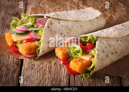 Sandwich roll with fish fingers, cheese and vegetables close-up on the table. horizontal Stock Photo