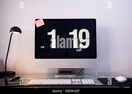 modern flat screen computer on a glass desk with time on the screen Stock Photo
