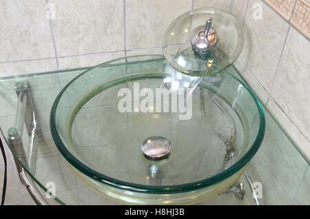 Water flows from the tap above the washbasin in the bathroom Stock Photo