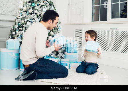 Father and son unwrapping a present lying on the floor Stock Photo