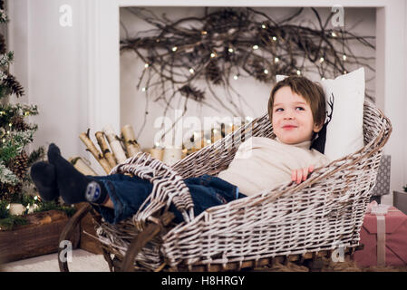 Little baby sits in a sleigh on Christmas decorations. Stock Photo