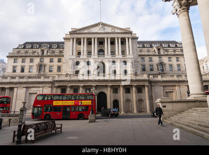 Front view of the Bank of England, Uk's Central Bank with iconic red double-decker London bus in the foreground. Stock Photo