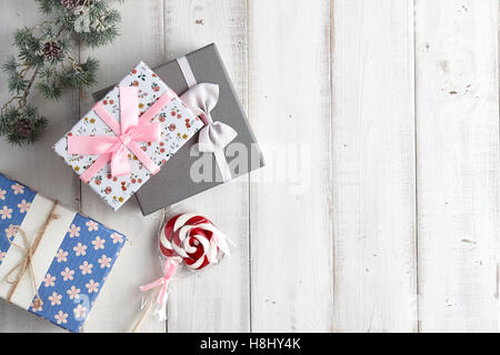 Christmas gift boxes and lollypop under fur tree branch on white wooden background Stock Photo